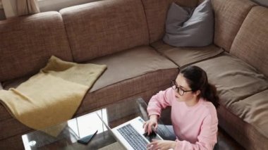 Top view of tired Caucasian young woman removes eyeglasses and rubs her eyes. Zoom in shot to womans face. Home workplace and remote work. Concepts of fatigue eyes and overwork.