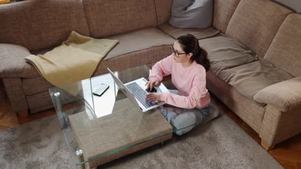 自由职业和远程工作 俯瞰年轻的高加索女人 戴着眼镜在笔记本电脑上工作 坐在沙发旁边的地板上 学生在家学习 — 图库视频影像