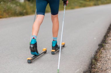 Legs of a biathlete athlete with ski poles, close-up. Concept of rollers ski and summer workout.