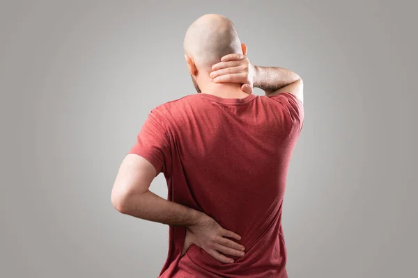 Back pain. The man holds his hands to the lower back and neck. Osteochondrosis. The concept of joint diseases.