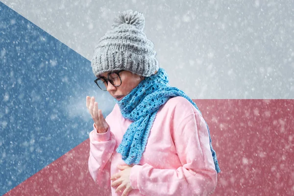 Energy crisis in Europe. Czech woman in hat and scarf is warming herself and cough. In the background is the flag of Czech Republic and a snowstorm. Concept of sanctions, refusal of gas and renewable energy.