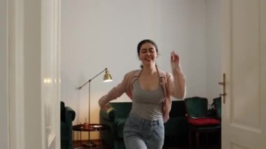 Happy young caucasian woman runs and falls on king size bed with comfortable mattress. Slow motion, follow shot. Relax in hotel during vacation