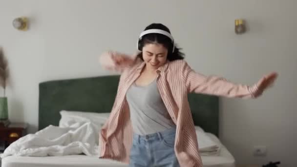 Happy Young Caucasian Woman Wearing Headphones Enjoying Dancing Big Bed — Wideo stockowe