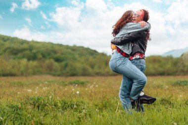 Mother and daughter hug each other tightly in a park. In the background, the forest and the sky. Copy space. The concept of psychology and family happiness.
