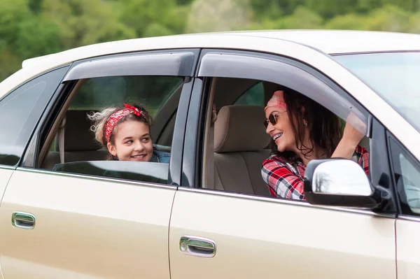 Family vacation and trip. Smiling mother and daughter drives in a rented car. Close up. The concept of purchase a new automobile.
