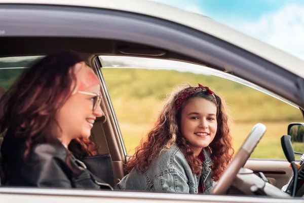 Family vacation and trip. Portraits of happy mother and teen daughter drives in a car. The concept of purchase a new automobile.