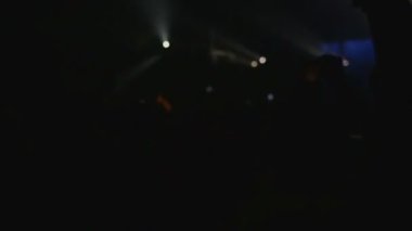 İnsanlar bir müzikal rock konserinde eğlenirler. Kadın, grubun performansını kaydetmek için akıllı telefonunu çıkardı. Kulüp atmosferi, beyaz ışık ışınları. Dikiz aynası. Eğlence konsepti.