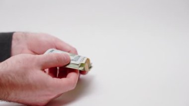 Person shows and counts dollar bills. Hands and currencies close-up on white background. Concept of investment and bribery.