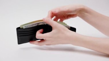 Woman's hands show leather wallet containing American dollars. Close-up. White background. Financing and investment concept.
