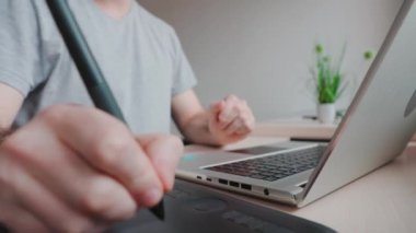 Man takes stylus from drawing tablet and begins to draw. Hand close-up. Concept of retouching and digital illustrations.