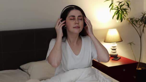 Pretty Caucasian Young Woman Lies Bed Wears Headphones Listens Lullaby — Wideo stockowe