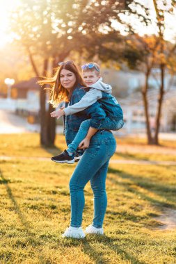 Outdoor family leisure. A happy young mother and son play in an autumn park. The concept of a childhood and motherhood.