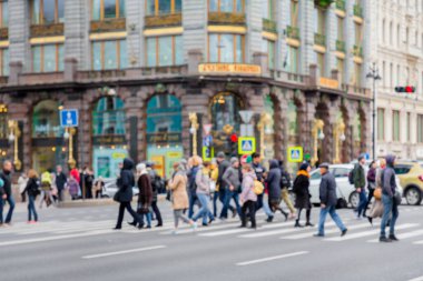 in the blur of the intersection where a group of people cross the street on the background of the building .