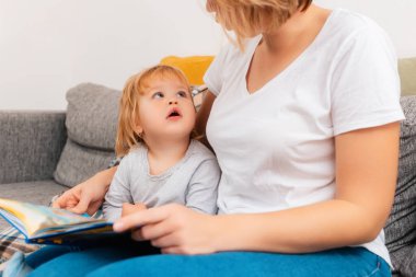 A woman is engaged in reading with a small autistic child. Pronunciation and speech therapy. Close up.