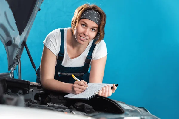 Portrait Young Caucasian Mechanic Woman Coveralls Signs Documents Leaning Car — Stockfoto
