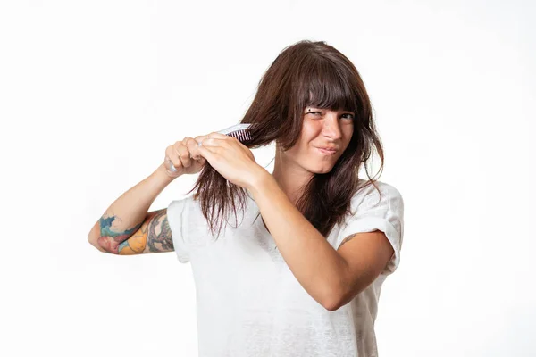 入れ墨をした若い女性は 髪のロックを組み合わせ 痛みを経験し 彼女の髪を引き出す 白地だ コピースペース 脱毛とケアの概念 — ストック写真