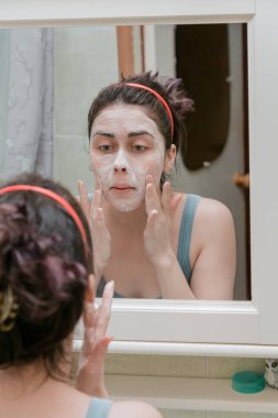 attractive girl making foam mask on her face to cleanse the skin of acne.