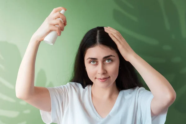 Young Beautiful Woman Sprays Care Cosmetics Her Hair Green Background — Stock fotografie