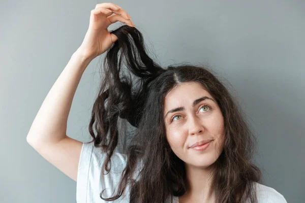 若い動揺した女性は当惑して彼女の髪の絡み合った鎖を保持します トリコロジーと脂漏性皮膚炎の概念 — ストック写真