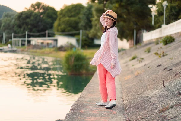 一个穿着夏装 头戴草帽的时髦女人走在河边的码头上 转过身来 后视镜暑假和快乐 — 图库照片