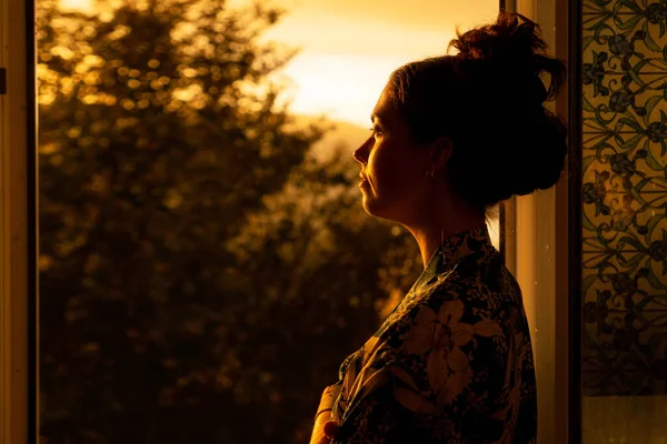 Caucasian Young Woman Looks Out Window Sunset Dreaming Side View — Foto Stock