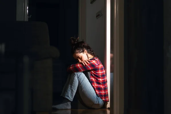 抑郁症和精神障碍 年轻的白人妇女绝望地坐在地板上 在黑暗的房间里受苦 侧视图 心理健康的概念 — 图库照片