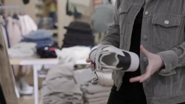 Kadın deri ayakkabıları tutuyor ve onları inceliyor. Eller ve ayakkabılar yakın plan. Alışveriş ve tüketim kavramı.