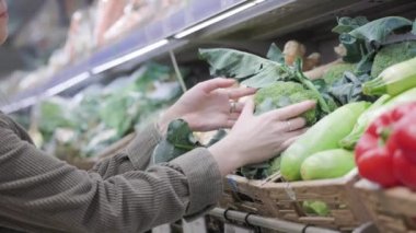 Kadın süpermarkette organik brokoli seçiyor. Hipermarkette doğal taze tarım ürünleri. Sebzeli el ve raflara yakın çekim