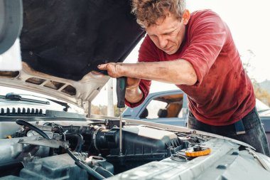 Özürlülük kavramı ve onların hayata uyum sağlaması. Sarışın, engelli bir adam bir arabayı tamir ediyor, tornavidayla çalışıyor. Ellerinde hiç parmak yok..