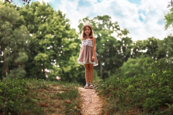 快乐的童年可爱的小女孩戴着草帽站在斜坡上打扮 背景是公园和天空 学校放假 自由和夏季的概念 — 图库照片