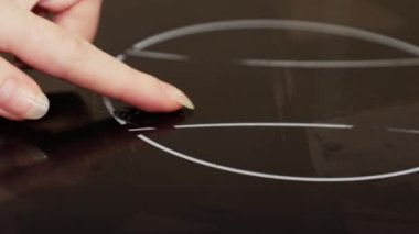 Woman's hand scrapes induction hob with finger. Dry dirty and stove close up. Concept of chores and cleaning service.