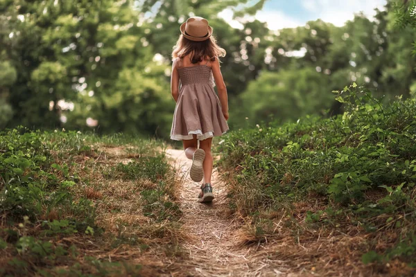 夏休みだ 藁帽子で女の子のバックビューと公園の中を歩くドレス 子供の日と子供の日の概念 — ストック写真
