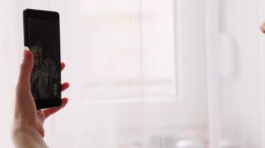 Kafkasyalı genç bir kadının cep telefonuyla yaptığı video görüşmeleri. Akıllı telefondan zum yap. Pencere ve ışık arka planda. Serbest ve çevrimiçi iletişim kavramı.