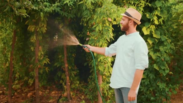 农夫用烟斗浇灌着一个充满激情的果树种植园 侧视图 有机园艺和园艺的概念 — 图库视频影像