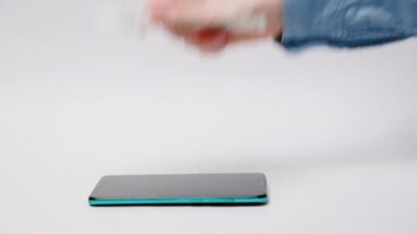 Cep telefonu uygulamaları ve bankacılık. Beyaz arka planda bir akıllı telefon var, kadın elinin Amerikan doları koyduğu bir telefon. Hücresel iletişim ve çevrimiçi para transferi kavramı.