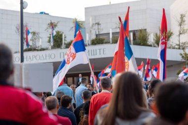 Ana binanın önünde insanların politik mitingi. Vatanseverlerin elinde Sırp bayrakları var. Demokrasi gösterisi ve vatanseverlik.