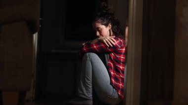 Depresyon ve zihinsel bozukluk. Kafkasyalı genç bir kadın çaresizlik ve acı içinde yerde oturup ağlıyor. Yan görüş. Psikolojik sağlık ve sorun kavramı.