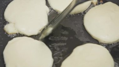 İnsan bir spatula dolusu gözlemeyle kızgın sebze yağıyla kızartma tavasına girer. Yakın plan. Üst Manzara. Yemek pişirme konsepti konforlu yemek