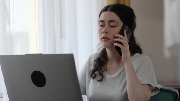 Серьёзная Молодая Белая Женщина Звонит Мобильный Телефон Работающий Ноутбуке Домашний — стоковое видео