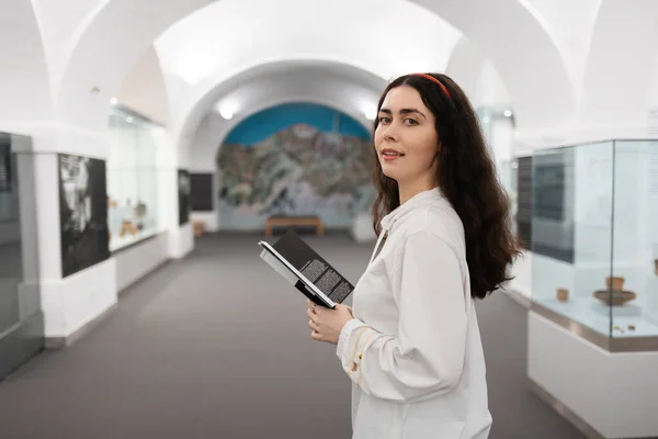 若い白人女性はパンフレットを持っており 博物館で教育旅行を回っています 背景にライトホール 文化展の概念 — ストック写真
