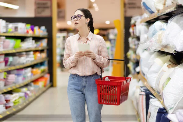 Mulher Branca Jovem Vestindo Óculos Mantém Cesta Supermercado Mantém Lista — Fotografia de Stock