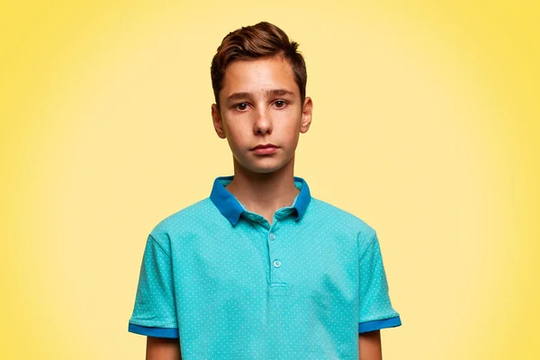 stock image Portrait of a Caucasian teenage boy in a blue T-shirt on a yellow background. Copy space.