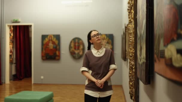 Молодая Красивая Кавказская Студентка Очках Прогуливаясь Музею Созерцает Древние Иконы — стоковое видео