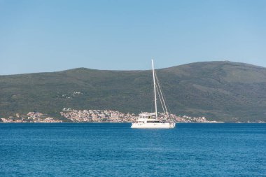 Mavi denizde, yeşil dağların arka planına karşı beyaz yelkenli. Yaz manzarası. Boşluğu kopyala.