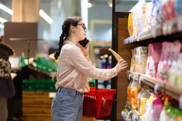 Compras Mulher Muito Caucasiana Escolhendo Comida Supermercado Falando Smartphone Vista — Fotografia de Stock