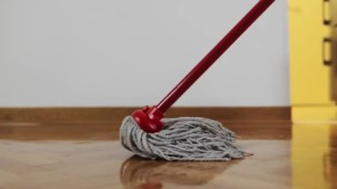 Temizlik servisi. Ev, parke ile ıslak bez yıkar. Yerleri paspaslamak için yakın plan. Atışı izle. Düşük açı görünümü.
