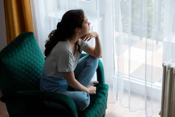 stock image Top view of Caucasian young woman sitting on green velour armchair and look at window. Concept of depression, psychology and mental health problems.