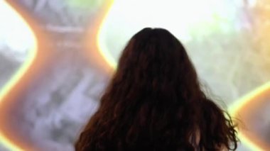 Kadın büyük ekranda siyah beyaz film izliyor. Arka görünüm