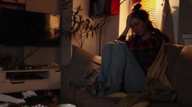 Psikoloji ve zihinsel sorunlar. Yalnız genç beyaz kadın kanepede oturuyor ve elleriyle başını kaşıyor. Obsesif kompulsif bozukluk ve depresyon.