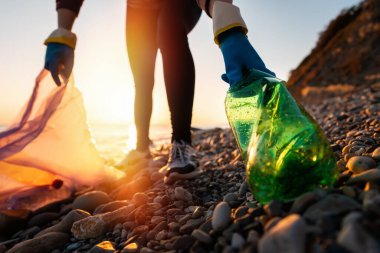 Ekoloji ve Dünya Günü 'nün korunması. Bir gönüllü deniz kenarında plastik şişe topluyor. Kıyı temizliği ve küresel çevre kirliliği kavramı.